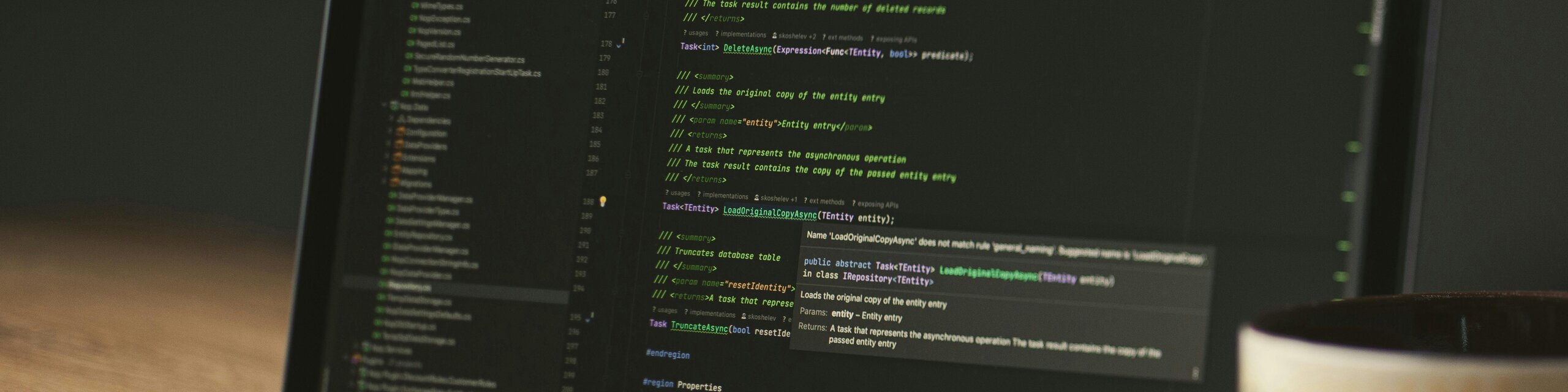 Entwickler-Arbeitsplatz mit Laptop, Code-Editor und Kaffeetasse